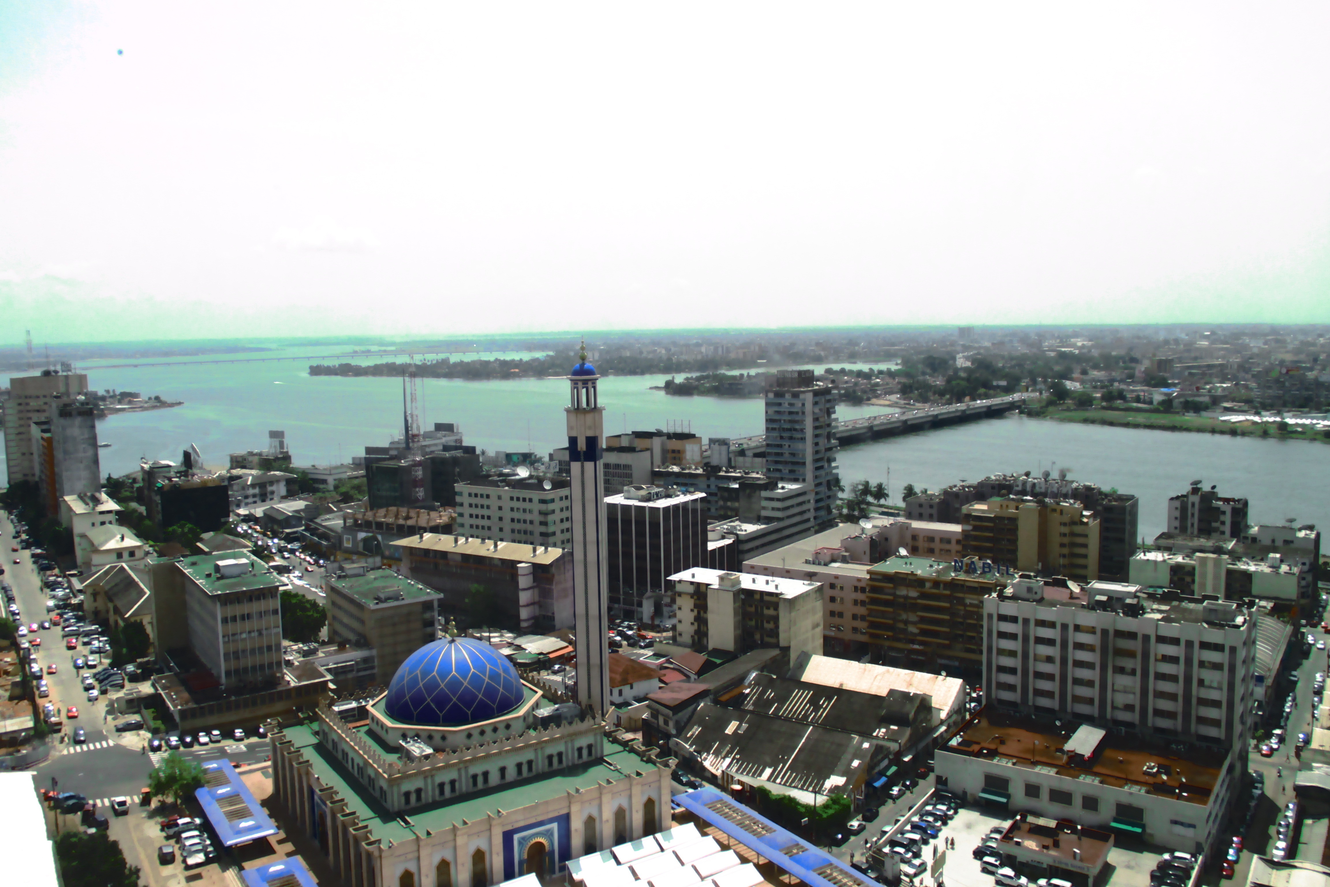 Another view from the green-tinted ADB Tower. The Mosquée du Plateau in the front; the large suburbs of Marcory and Koumassi are in the background on the other side of the Ébrié Lagoon. The line you see on the left is the brand new Henri Konan Bédié Bridge, named after the country's second president, still active in politics. 